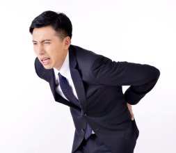 腰痛で腰を押さえる男性